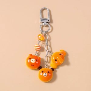 Detailed view of cute bear and pig charms on a warm orange keychain with silver metal ring