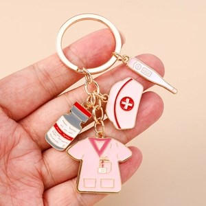 Detail of pink nurse hat, medical uniform and thermometer charms on a gold keychain