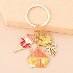 Close-up of scarecrow, house and wheat pendants on golden metal keychain charm