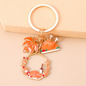 Detail showing enamel Thanksgiving charms with maple leaf and roast turkey on a gold keychain