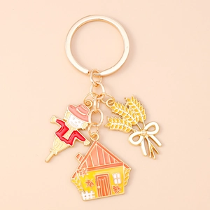Detail of harvest-themed keychain with scarecrow, house, and wheat ear charms