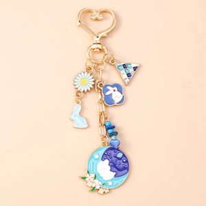 Détails du lapin en émail bleu et de la marguerite sur un porte-clés cœur doré