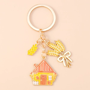 Detail showing enamel scarecrow house keychain with golden maple leaf and wheat charms