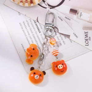 Detailed view of resin animal keychains featuring bear and pig charms with orange beads