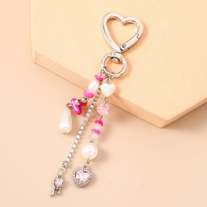 Pink heart keychain with waterdrop pearls and rhinestones on a soft pastel background