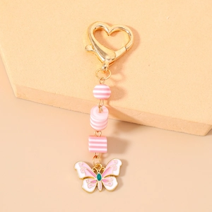 Détail du fermoir cœur doré avec perles rayées roses et pendentif de papillon