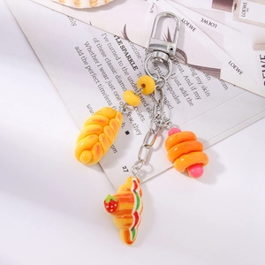 Detail of faux dessert keychain with croissant, bear bread and strawberry resin charms