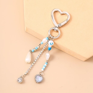 Detail of silver heart keychain featuring water drop pearl and blue beaded charms