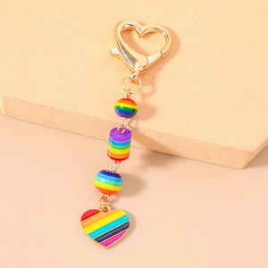 Porte-clés à perles arc-en-ciel avec fermoir cœur doré sur des marches beiges