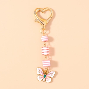 Détail d'un pendentif papillon rose avec perles rayées et fermoir cœur doré