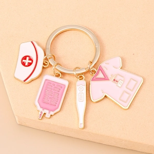 Close-up of pink nurse outfit and medical charm keychain with gold plated finish