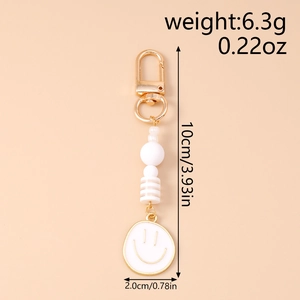 Detail view of stylish white beaded smiley face keychain with gold lobster clasp and dimensions