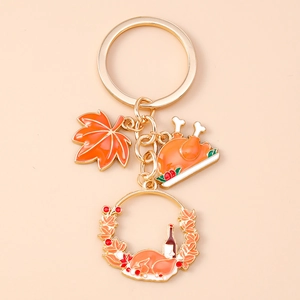Detail of Thanksgiving keychain featuring orange maple leaf and roasted turkey charms