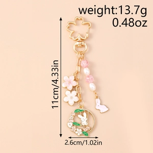 Detail view of cherry blossom bunny keychain with golden alloy and pink enamel charms