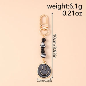 Detail of beaded smiley face keychain featuring black striped beads and gold lobster clasp