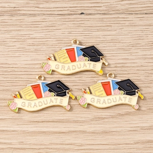 Détail de trois breloques émaillées avec toque de diplômé et livres pour bijoux DIY