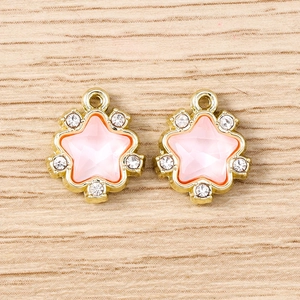 Detailed macro view of two gold pentagram pendants with pink crystals and rhinestones