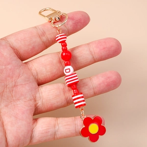 Porte-clés à fleurs avec perles rouges et blanches et fermoir doré tenu à la main