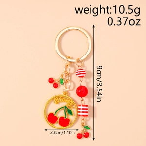Detail view of a golden cherry keychain with enamel charms and Cherry text pendant