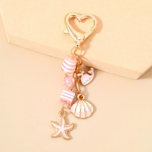 Detail of a pink ocean-themed keychain featuring whale, shell, and starfish charms