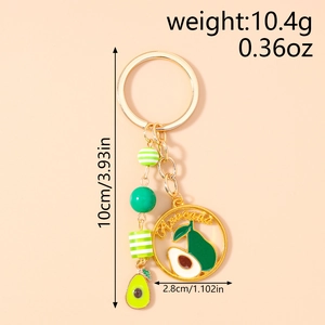 Detail of golden avocado keychain with 3D pendant, lettered disc and striped beads