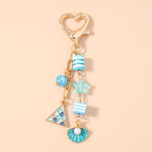 Close-up of golden heart clasp and mint green shell pendant with sea elements