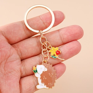 Detail of cartoon hedgehog keychain with small yellow flower pendant on a gold ring