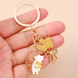Detail of golden alloy hedgehog and wheat keychain with enamel drip finish for bags