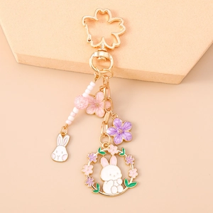 Detail of bunny enamel keychain with cherry blossom charms and gold metal flower clasp