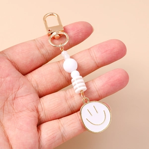 Fashionable beaded smiley face keychain with gold spring clasp and white enamel charm