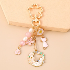 Detail of pink floral cherry blossom keychain with cat pendant and golden metal hook