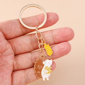 Detailed view of hedgehog keychain with champagne gold metal and enamel wheat spike charm