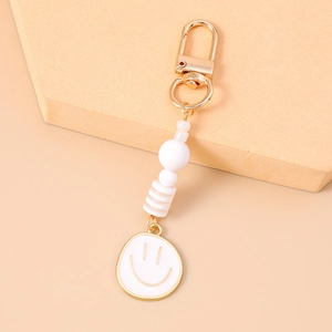 Detail of beaded smiley face keychain with gold lobster clasp on peach background