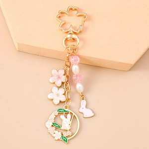 Detail of champagne gold cherry blossom rabbit keychain with enamel flowers and pearls
