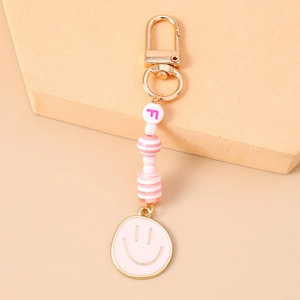 Detail of pink beaded keychain featuring letter F bead and smiley face charm on golden clasp