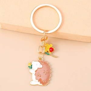 Detailed view of hedgehog keychain with yellow flower and ladybug on a warm textured base