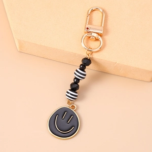 Detail of beaded smiley face keychain with gold hardware and black striped charms