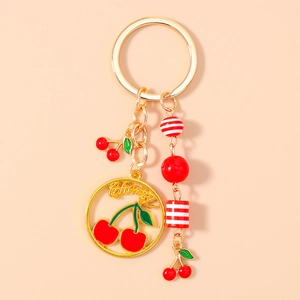 Detailed close-up of golden metal cherry keychain with red cherry charms and beads