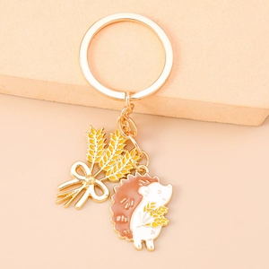 Close-up of golden hedgehog and wheat ear enamel pendants on a premium metal keychain