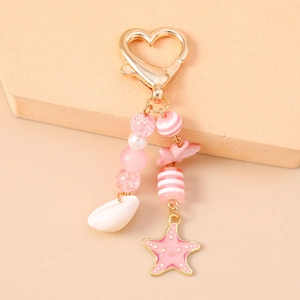 Dettaglio di portachiavi rosa a tema marino con perle di conchiglia e stella marina su base