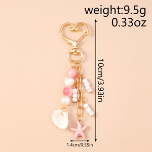 Detail of pink starfish and white shell charms on a gold beaded heart keychain