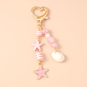 Dettaglio di ciondoli con conchiglie rosa e stelle marine su chiusura a cuore dorato