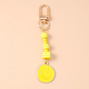 Detail of yellow beaded keychain with smiling face charm and golden lobster clasp