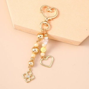 Detail of beaded heart keychain with pearls, gold charms, and transparent stars