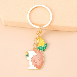 Detail of cute hedgehog and corn pendants on a gold keychain with oil drip finish
