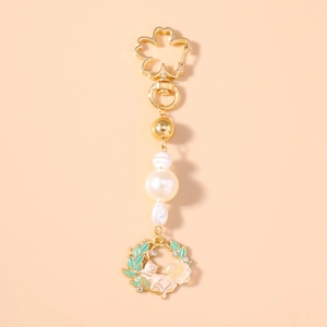 Detail of cherry blossom hook and cat pendant with faux pearls on golden keychain