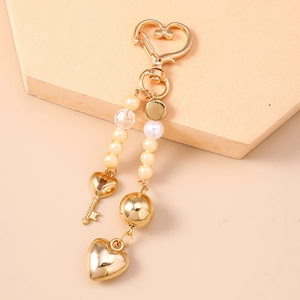 Detail of beaded heart keychain with pearls, gold charms and heart-shaped spring clasp