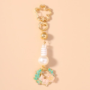 Close-up of golden sakura flower clasp with a pink cat charm and a large white pearl