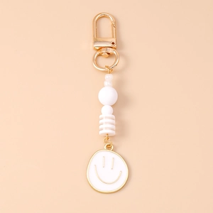 Detail of beaded smiley face keychain with gold lobster clasp and white beads