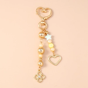 Detailed view of a golden heart keychain with pearl beads and star-shaped charms